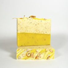 Charger l'image dans la galerie, Savon de fantaisie fait à la main aux couleurs blanc et jaune. Décoré d'avoine et de pétales de fleurs de calendule en poudre.