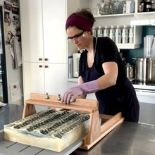 Charger l'image dans la galerie, Ariane, notre savonnière, est entrain de couper les savons Bootlegger à l'aide de sa grande tranche à savon.