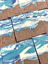 Charger l'image dans la galerie, Savons de fantaisie faits à la main. Décoré d'un joli motif marbré avec des couleurs blanche, bleue turquoise et brun. La partie brune à des petit grains de café moulus. Une estampe de la forme des Îles-de-la-Madeleine apparaît sur chaque savon.